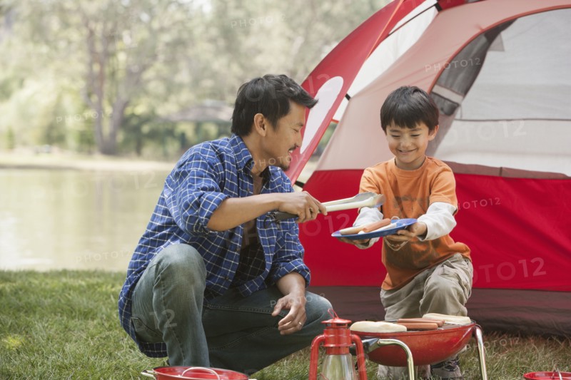 Father and son cooking at campsite