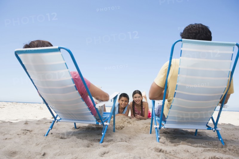 Parents watching children from lawn chairs on beach
