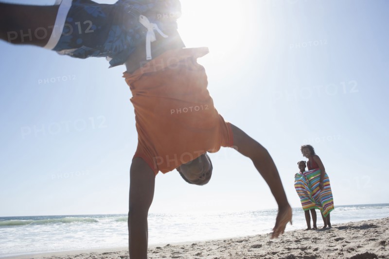 Boy doing cartwheel on beach