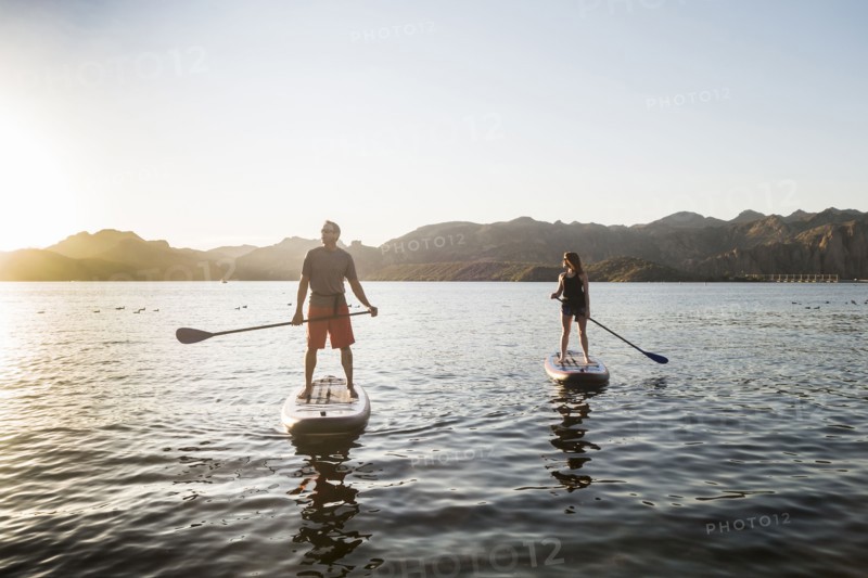 Couple standing on paddleboards in rover