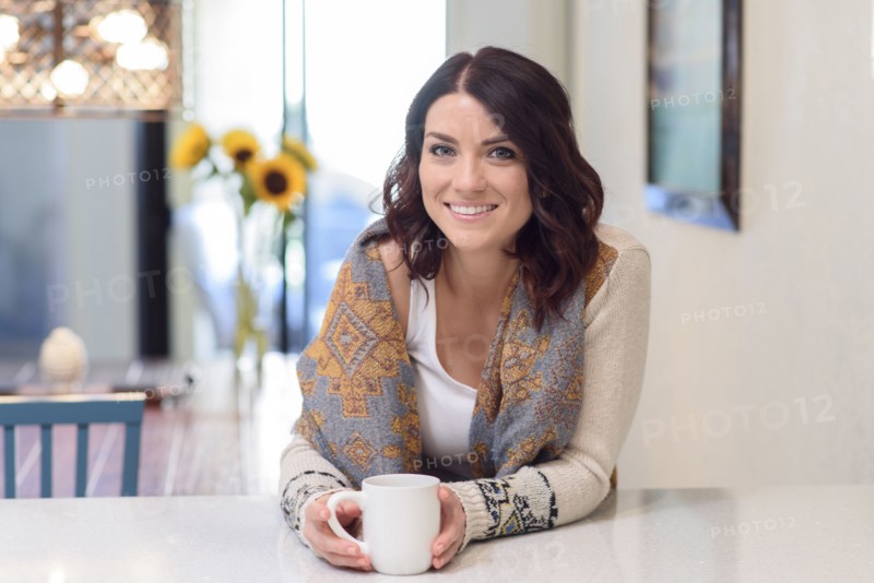 Caucasian woman leaning on counter drinking coffee