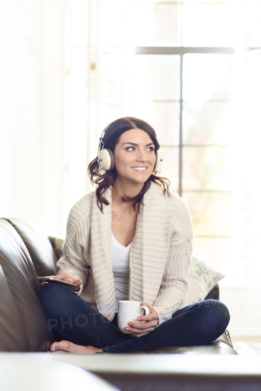Caucasian woman sitting on sofa listening to headphones