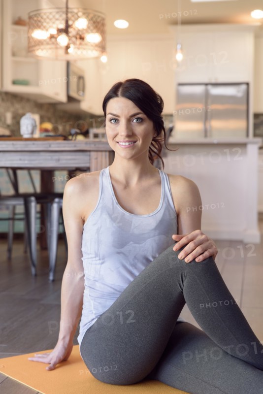 Smiling Caucasian woman sitting on exercise mat