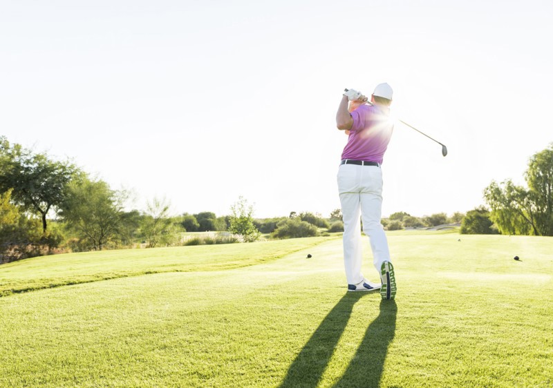Hispanic golfer teeing off on golf course