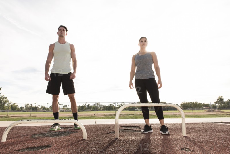 Couple standing nears exercise bars outdoors