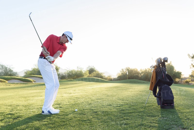 Hispanic man hitting ball on golf course