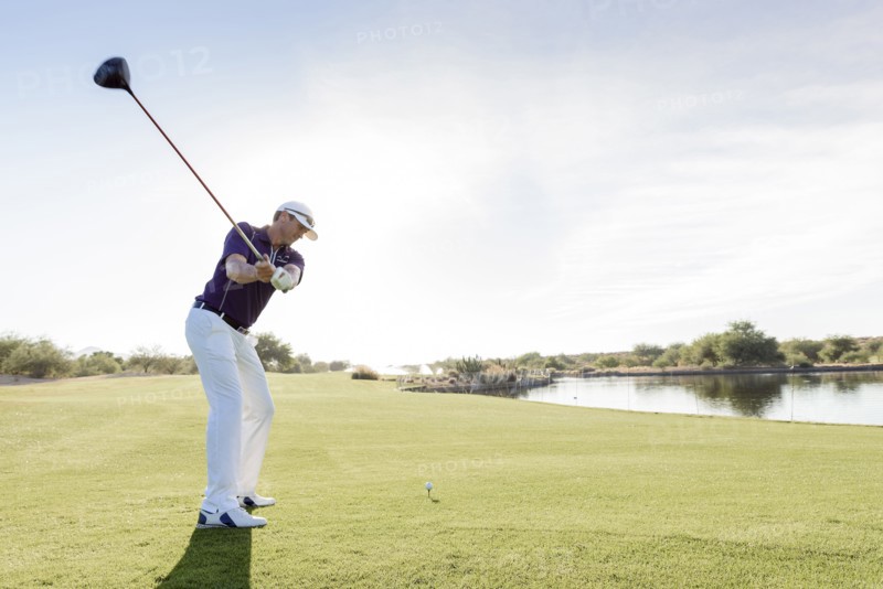 Hispanic man teeing off on golf course