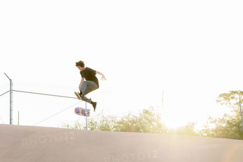 Hispanic man performing mid-air trick on skateboard