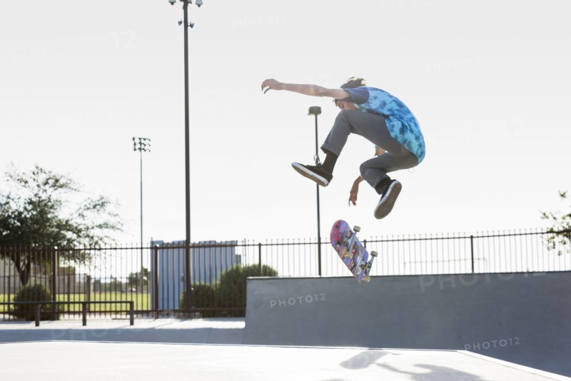 Hispanic man performing mid-air trick on skateboard