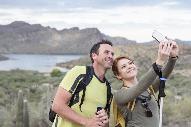Hikers posing for cell phone selfie in desert