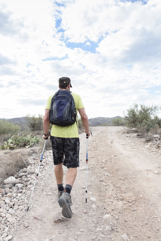 Hispanic man hiking on rocky path in desert