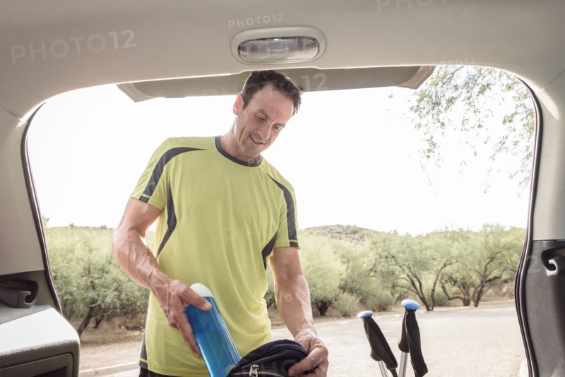 Hispanic man pulling water bottle from backpack in car