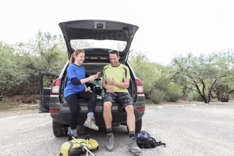 Hikers sitting in car texting on cell phones