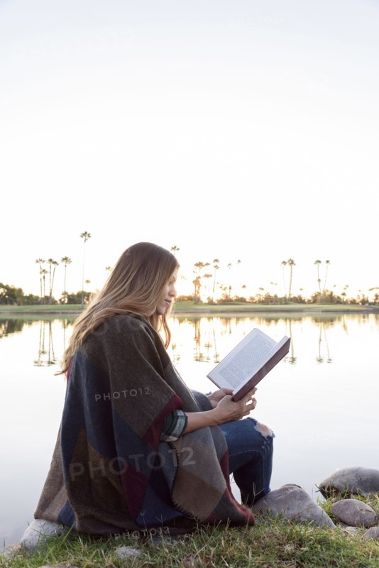 Hispanic woman sitting bear lake reading book