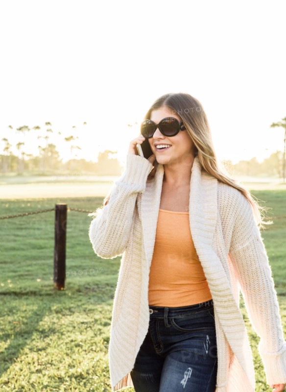 Smiling Hispanic woman wearing sunglasses talking on cell phone