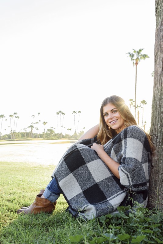 Hispanic woman leaning on tree