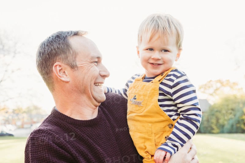 Laughing Caucasian father holding son