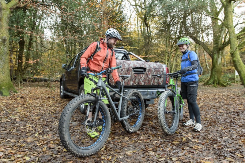 Caucasian couple holding bicycles near pickup truck