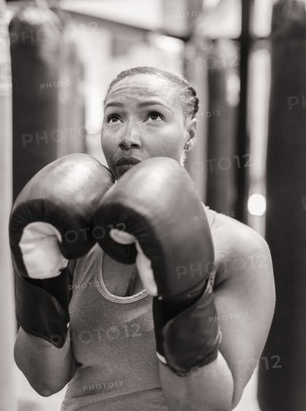 Portrait of Black woman wearing boxing gloves looking up