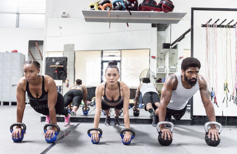 Man and women doing push-ups with kettlebells