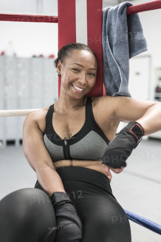 Black woman leaning in corner of boxing ring