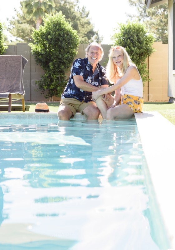 Caucasian couple smiling with legs in swimming pool