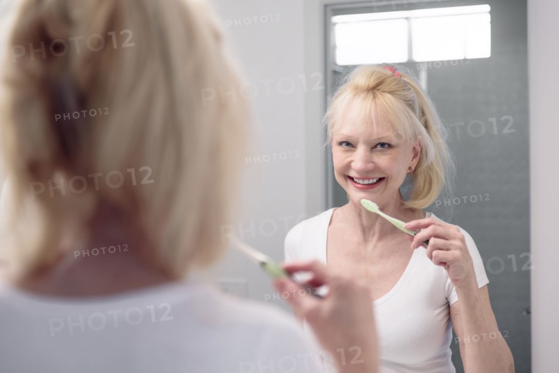 Caucasian woman brushing teeth in mirror