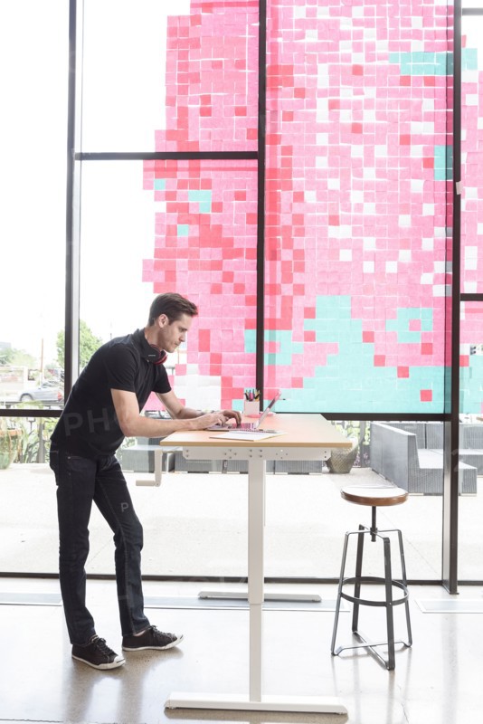 Caucasian man using a laptop at standing workstation