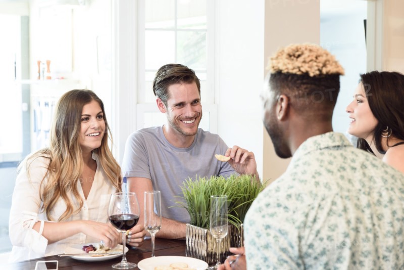 Friends smiling and talking with wine and snacks