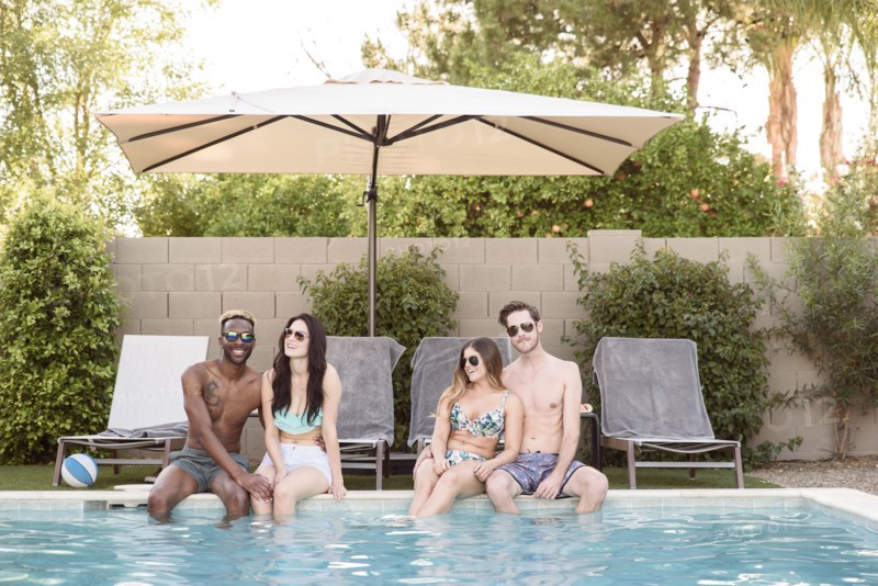 Smiling friends sitting and relaxing poolside