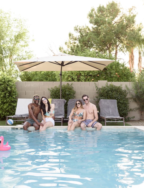 Smiling friends sitting and relaxing poolside