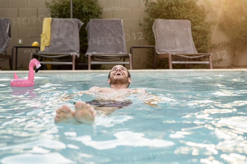 Smiling Caucasian man floating in swimming pool