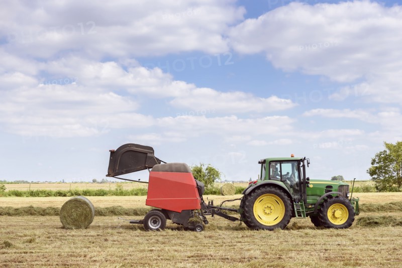 Caucasian man driving tractor baling hay
