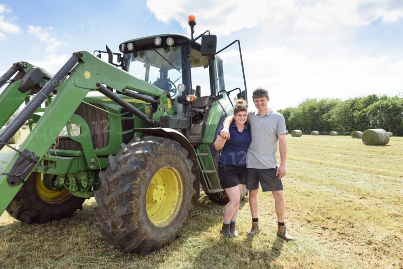 Smiling Caucasian couple posing near tractor