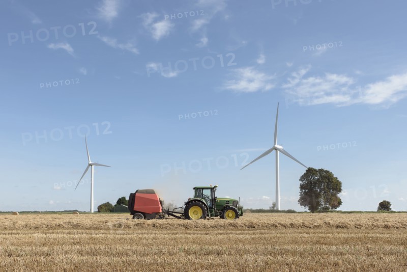 Caucasian man driving tractor near wind turbines