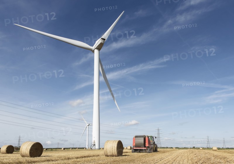 Bales of hay and tractor near wind turbine