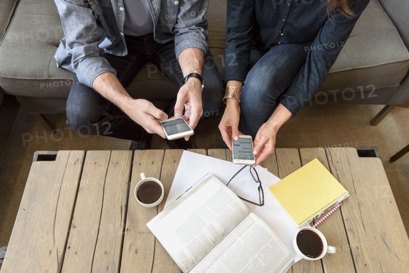 Hands of Caucasian couple texting on cell phones