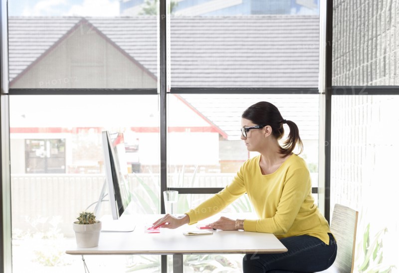 Caucasian woman writing on adhesive notes at desk