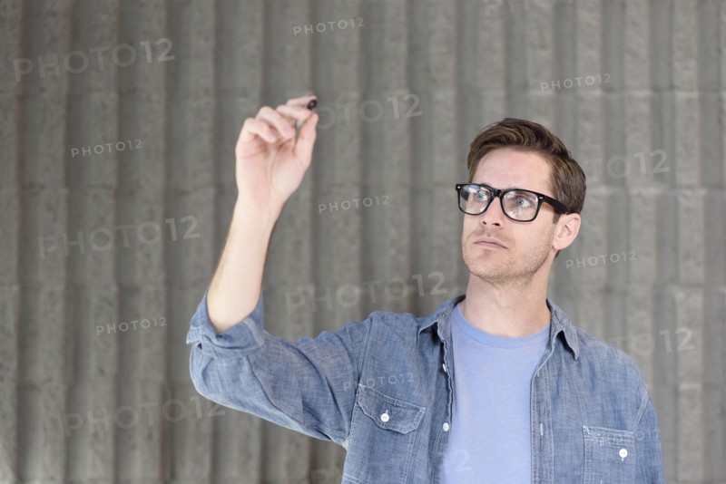 Caucasian man writing on glass wall