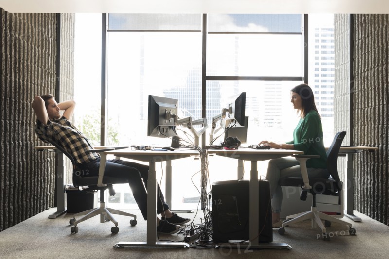 Caucasian man and woman using computers in office
