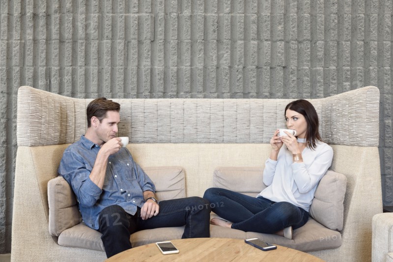 Caucasian couple relaxing on sofa drinking coffee