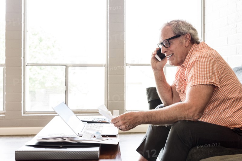 Smiling and Caucasian man sitting on sofa talking on cell phone