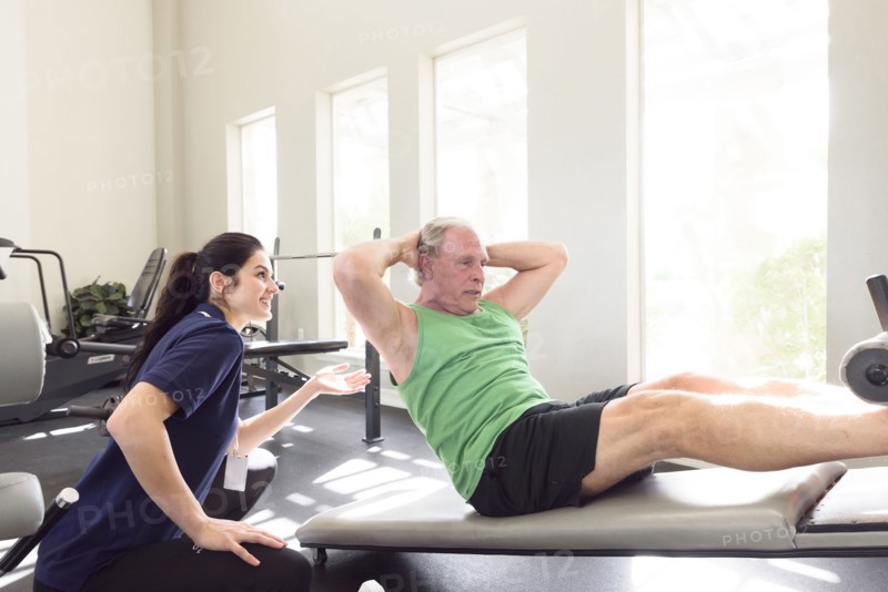 Caucasian trainer watching man doing sit-ups