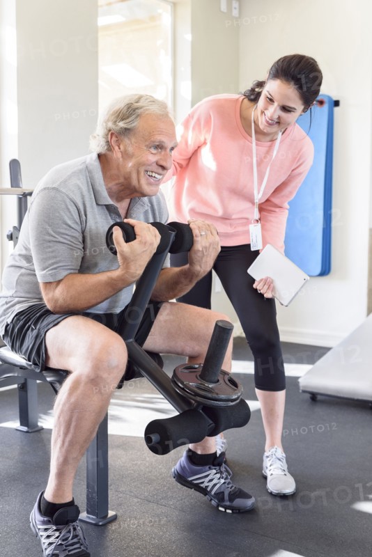 Caucasian trainer watching man strengthen arms