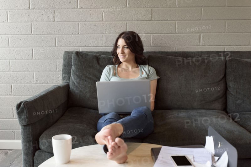 Caucasian woman sitting on sofa using laptop