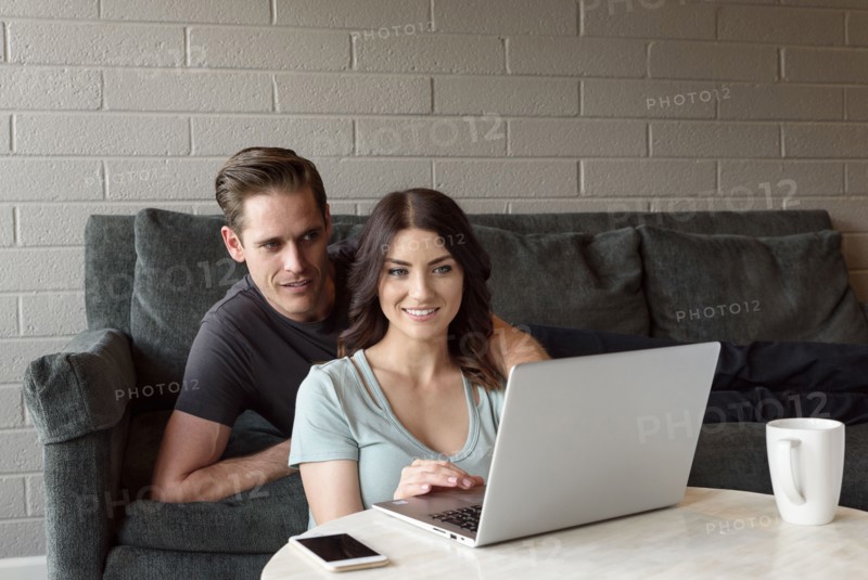 Caucasian couple on sofa using laptop