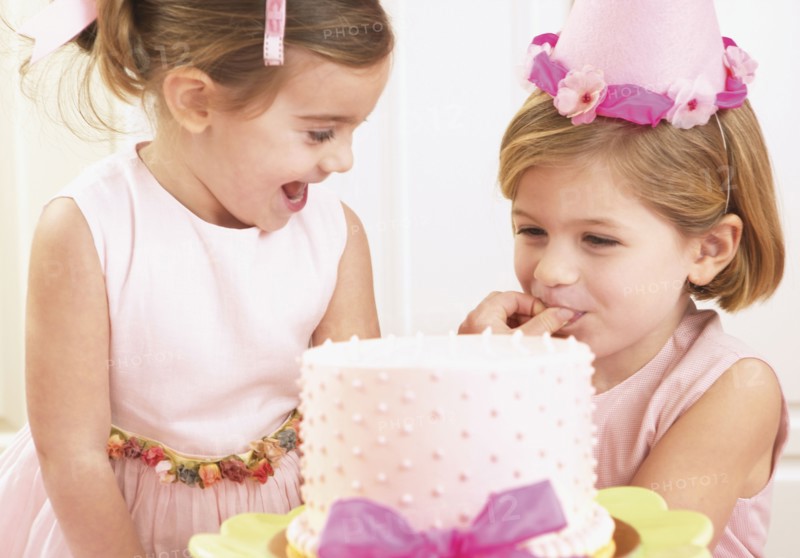 Young girls picking at a birthday cake