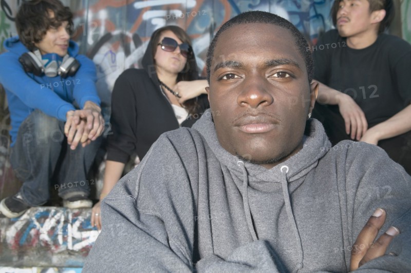Young African man with friends next to graffitied wall