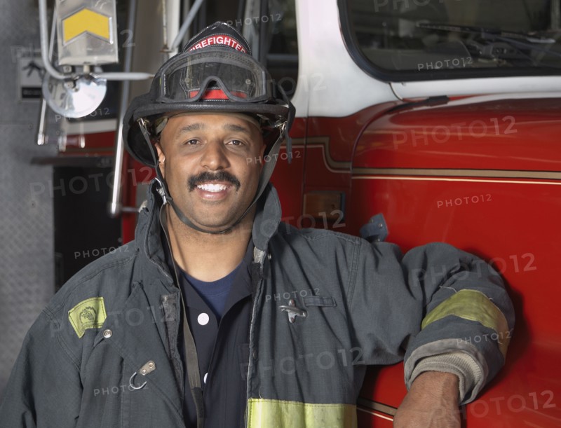 African male firefighter leaning against fire truck