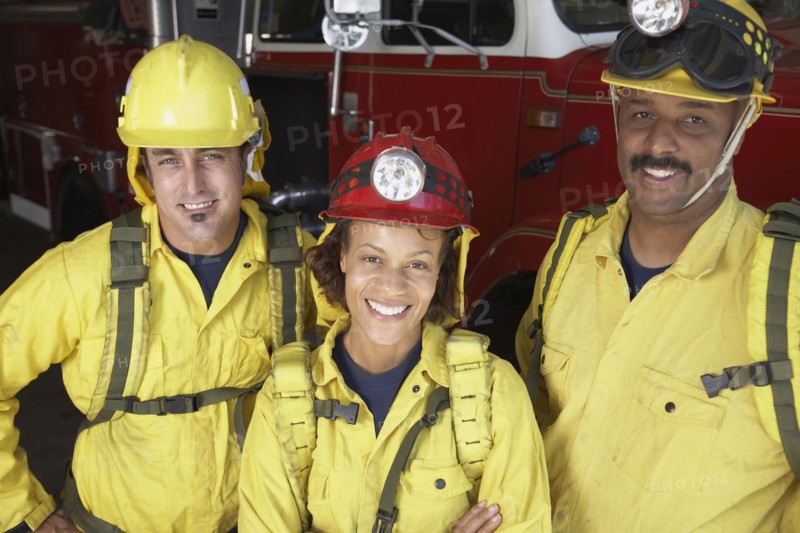 Portrait of firefighters next to fire truck